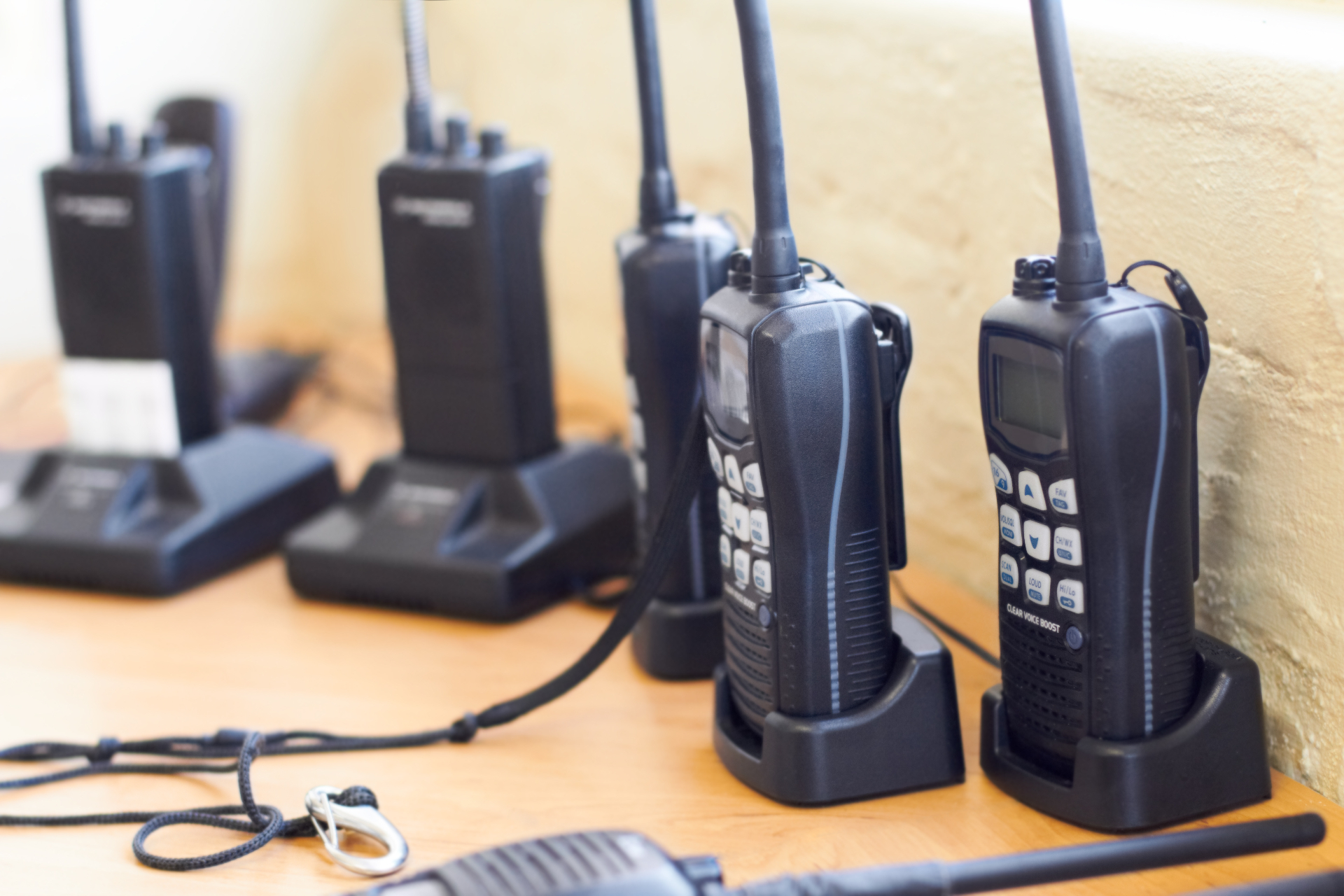 Two-way radios charging upright in their docking stations on a wooden shelf